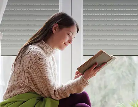 Femme en train de lire un livre devant une fenêtre à Strasbourg